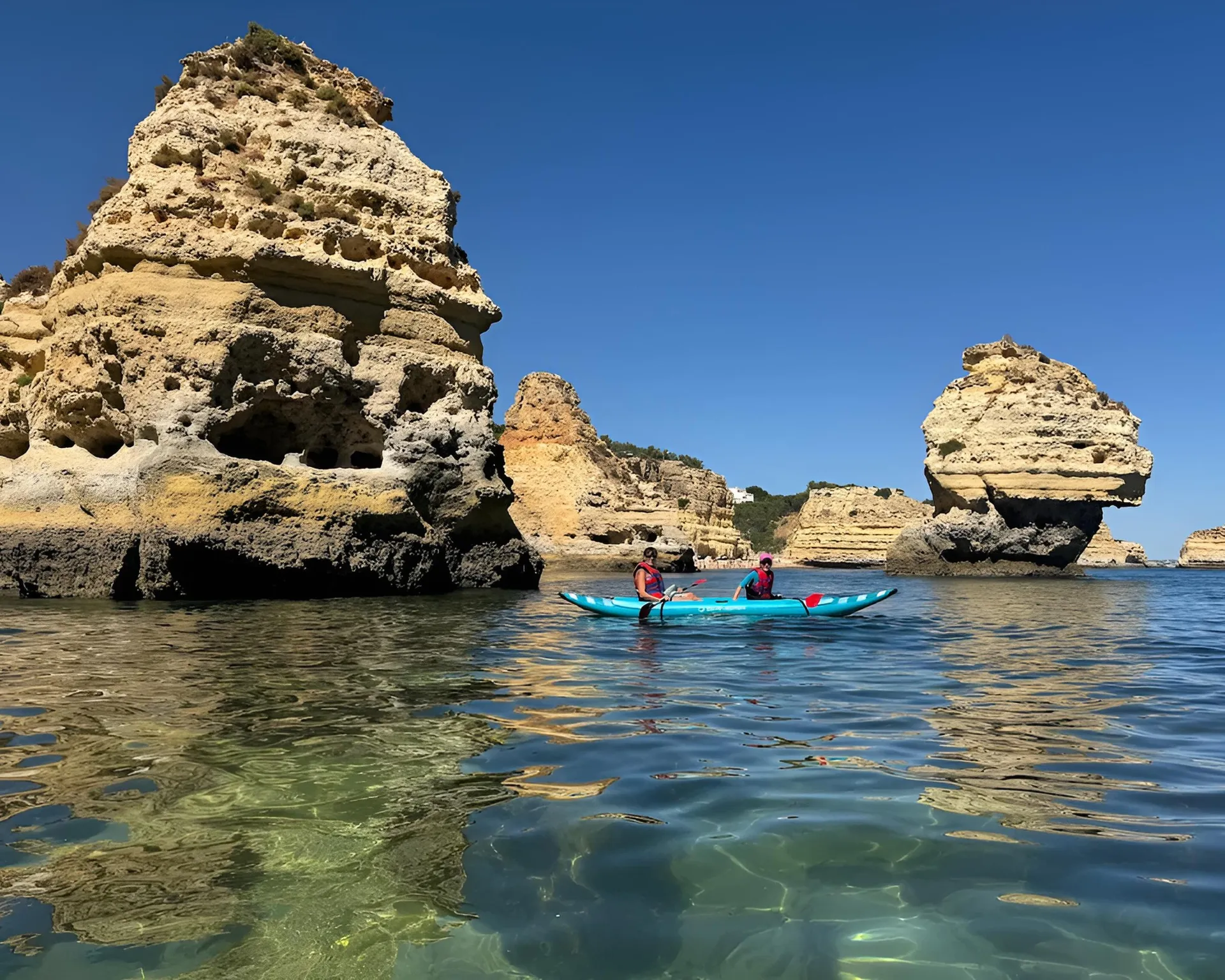 Couple in a tandem kayak between rock pillars in crystal-clear water