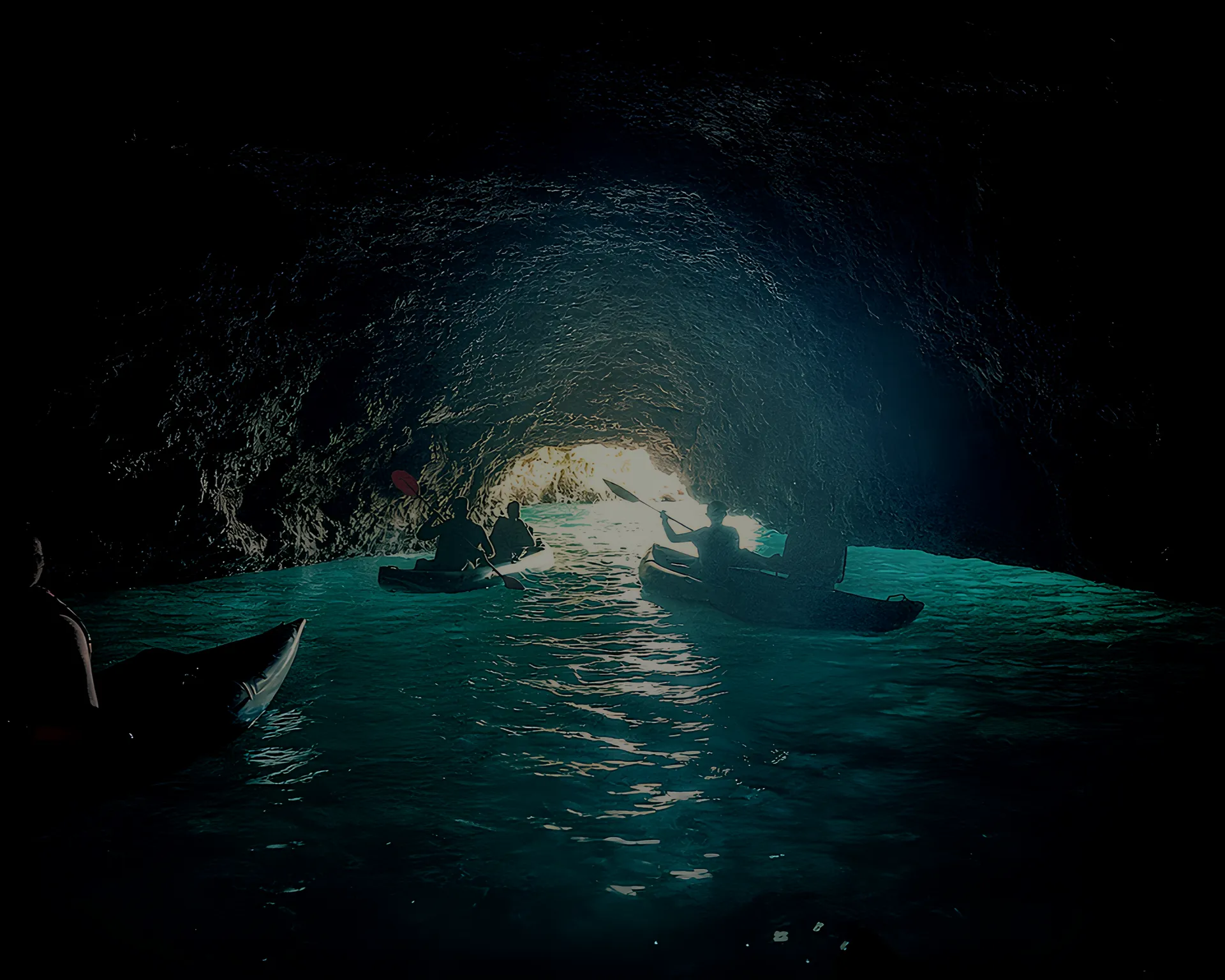 Dark Pirate Cave with kayak silhouettes and turquoise water