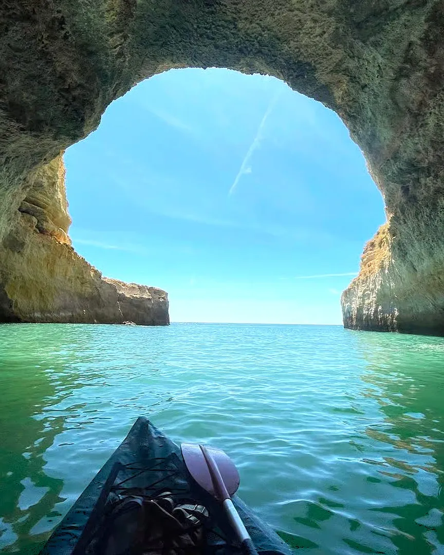 First-person kayak view approaching a sea arch in the Algarve
