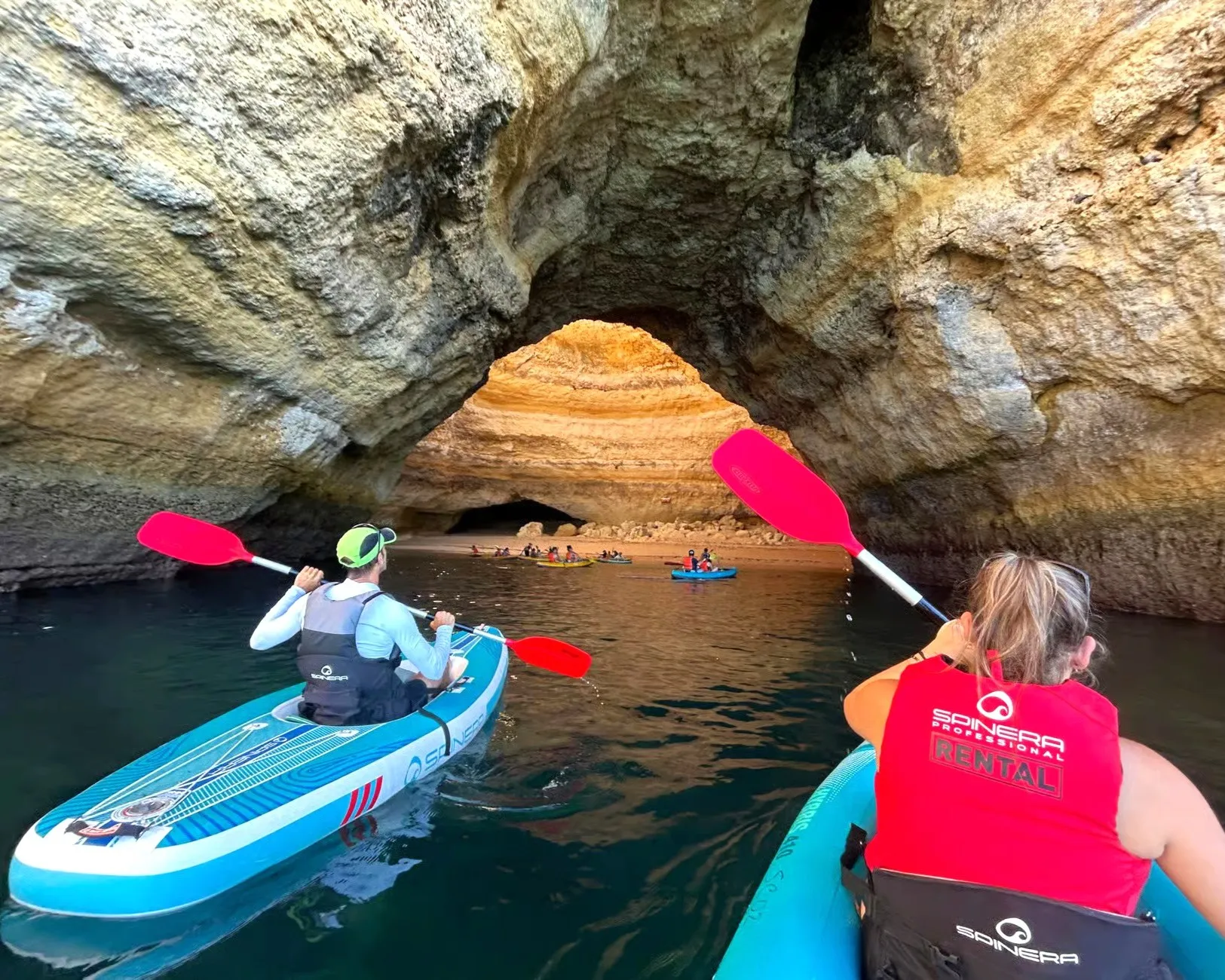 Kayakers paddling through a natural rock arch near Benagil