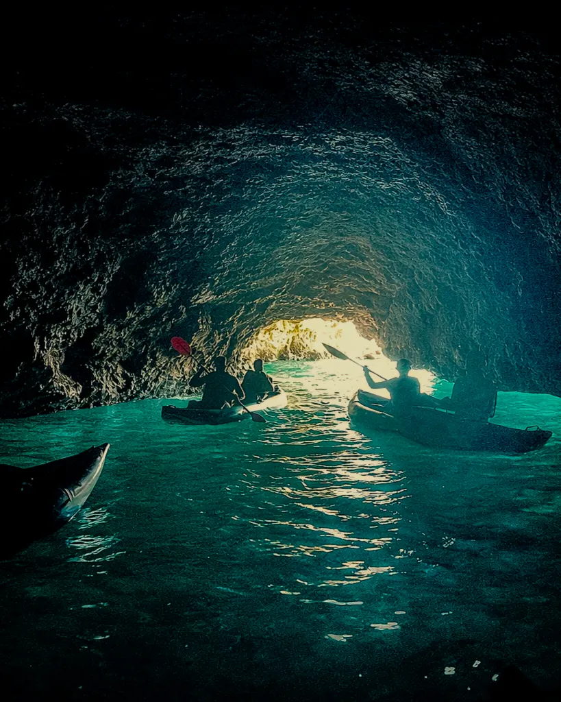 Silhouette of kayakers inside a dark sea cave in the Algarve